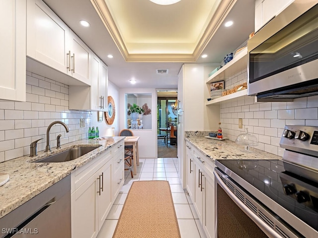 kitchen with white cabinetry, stainless steel appliances, a raised ceiling, and sink