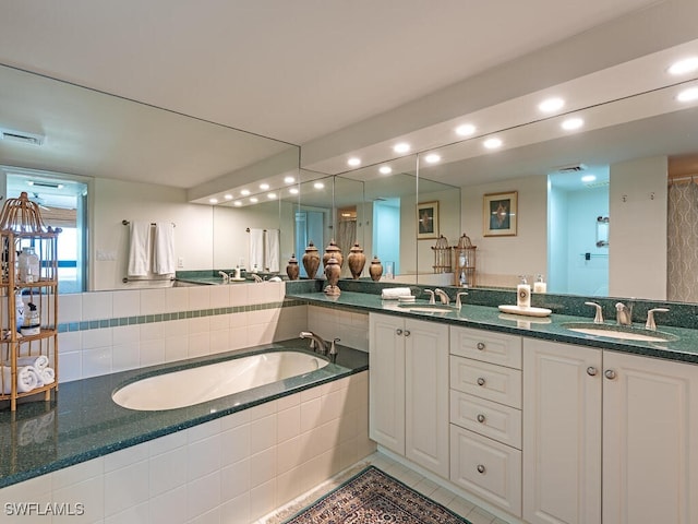 bathroom featuring a relaxing tiled tub, tile patterned floors, and vanity