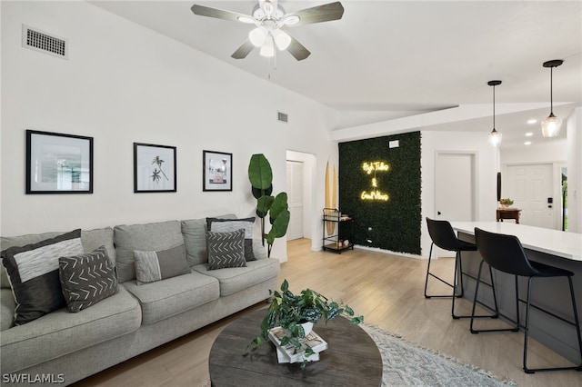 living room featuring vaulted ceiling, ceiling fan, and light wood-type flooring