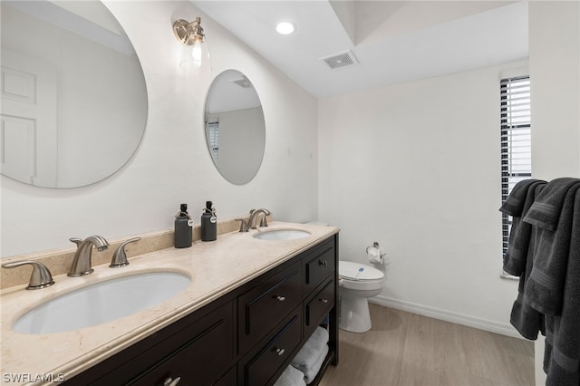 bathroom featuring wood-type flooring, double sink vanity, and toilet