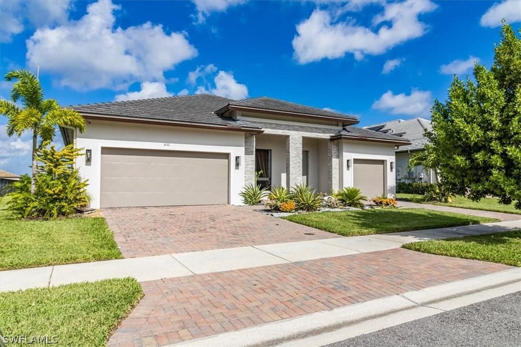 prairie-style home featuring a garage and a front yard