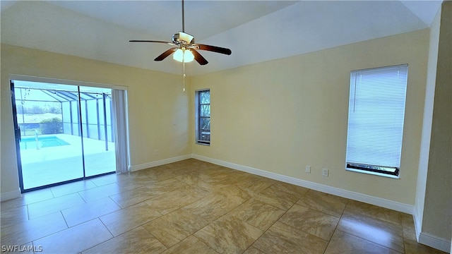 tiled empty room with ceiling fan and vaulted ceiling