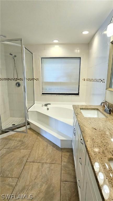 bathroom with independent shower and bath, vanity, tile patterned flooring, and tile walls