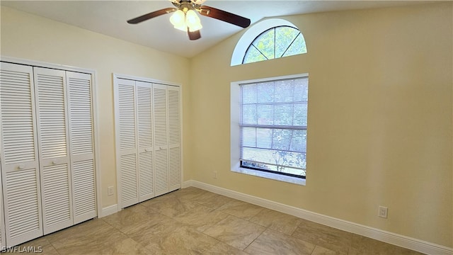 unfurnished bedroom featuring two closets, ceiling fan, lofted ceiling, and light tile patterned floors