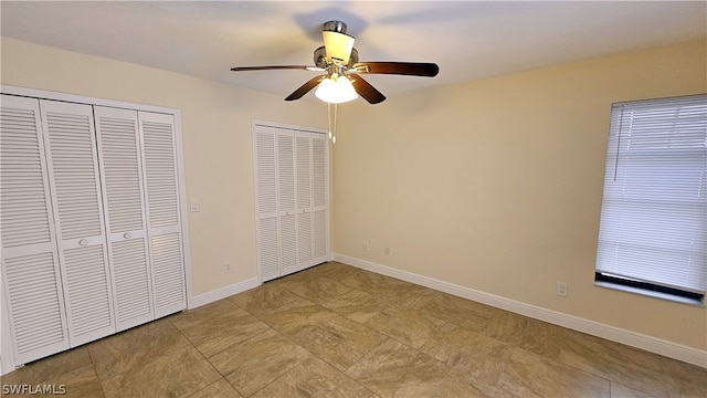 unfurnished bedroom with multiple closets, light tile patterned floors, and ceiling fan