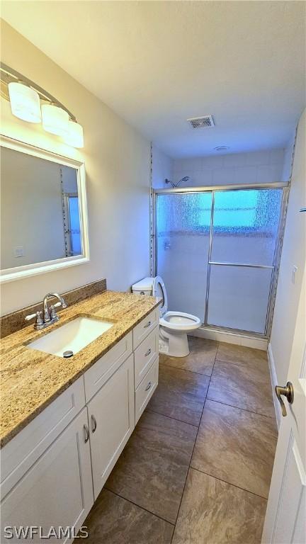 bathroom featuring vanity, toilet, and an enclosed shower