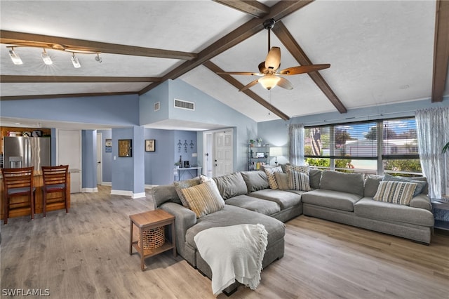 living room featuring rail lighting, light wood-type flooring, beam ceiling, high vaulted ceiling, and ceiling fan