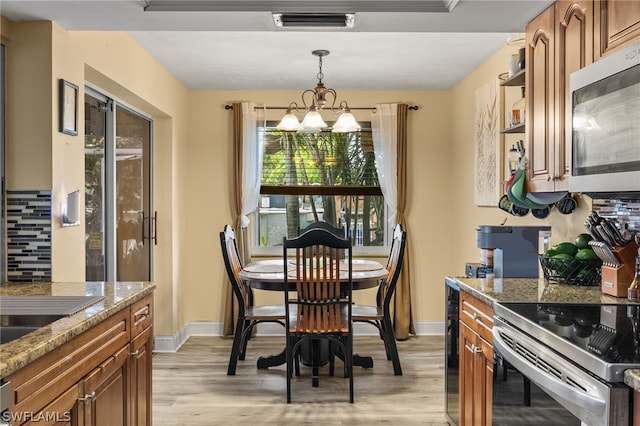 dining room with light wood-type flooring and a chandelier