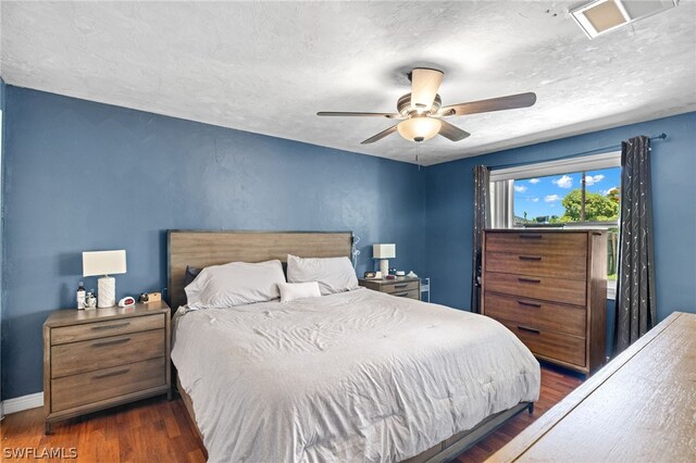 bedroom with dark hardwood / wood-style floors, a textured ceiling, and ceiling fan