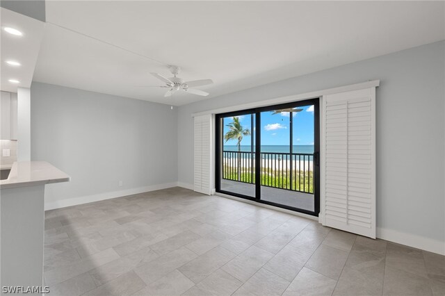 spare room featuring a water view, ceiling fan, and light tile patterned floors