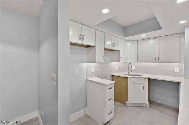 kitchen featuring light tile patterned flooring, tasteful backsplash, sink, and white cabinets