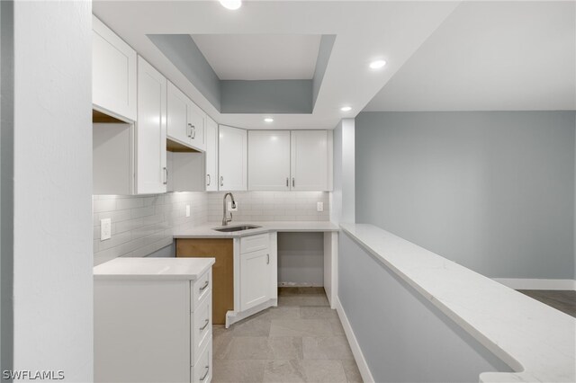 kitchen with white cabinets, backsplash, light tile patterned flooring, and sink