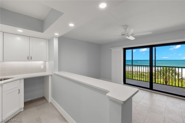 interior space featuring a water view, white cabinets, backsplash, and kitchen peninsula