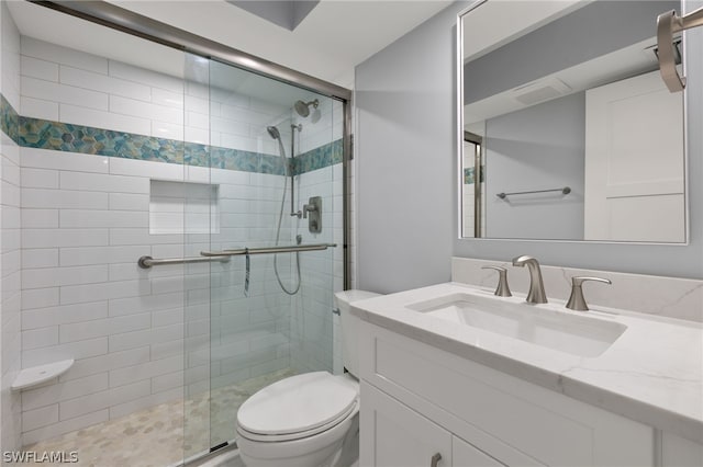 bathroom featuring a shower with shower door, vanity, and toilet