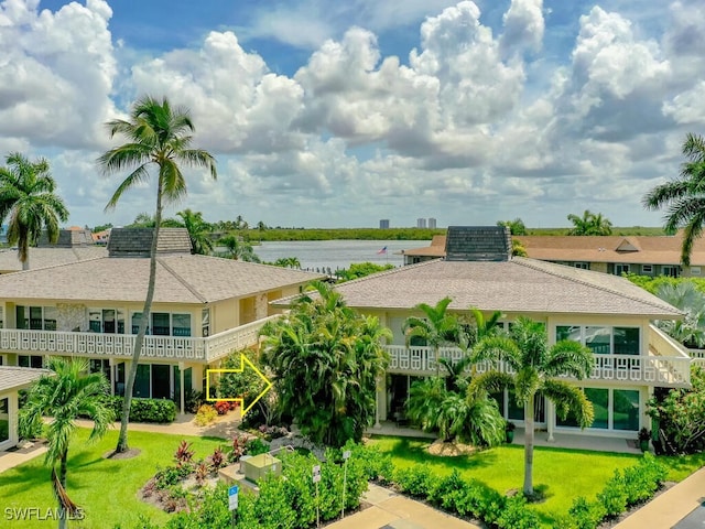 exterior space with a balcony, a water view, and a front lawn