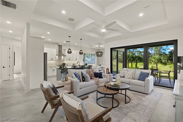 living room with ceiling fan, a raised ceiling, coffered ceiling, and light tile patterned floors