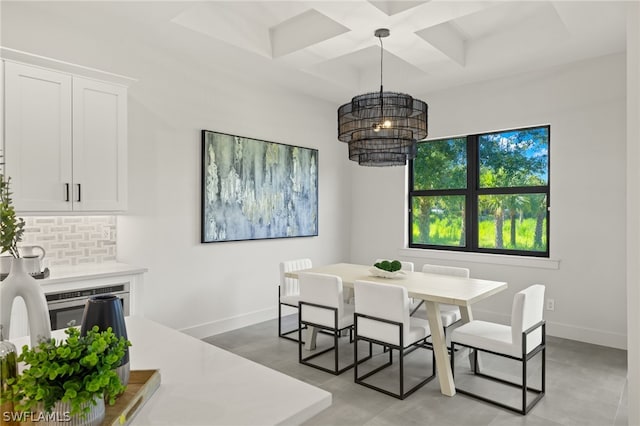 dining space featuring light tile patterned flooring, coffered ceiling, and a chandelier