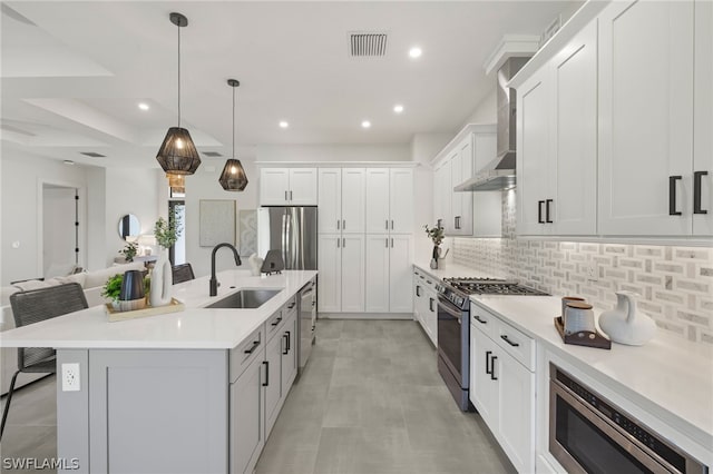 kitchen with stainless steel appliances, light countertops, a center island with sink, and visible vents