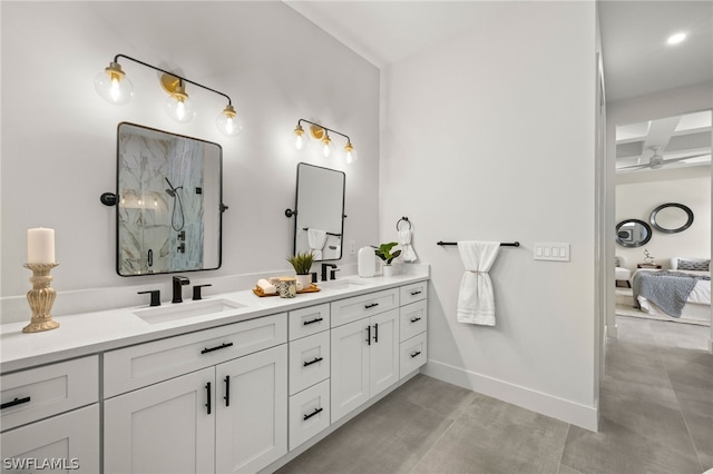 full bathroom featuring a marble finish shower, double vanity, a ceiling fan, a sink, and baseboards