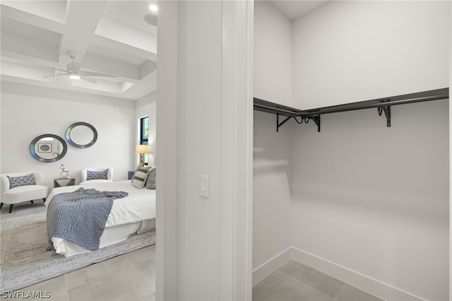 walk in closet featuring beam ceiling, ceiling fan, light tile patterned floors, and coffered ceiling