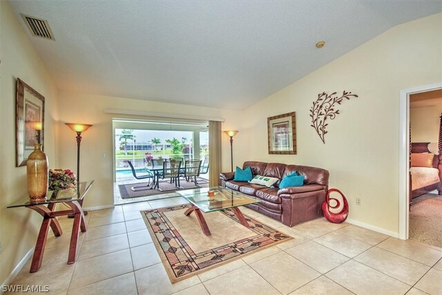 living room featuring light tile patterned flooring, lofted ceiling, and a textured ceiling