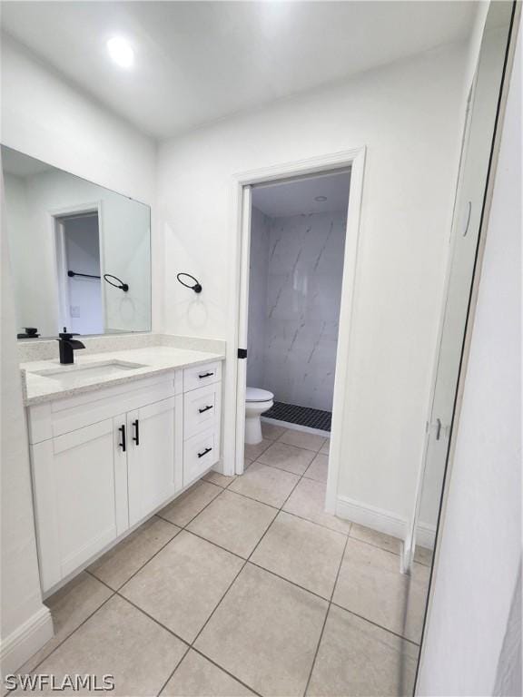 bathroom with vanity, tile patterned flooring, toilet, and tiled shower