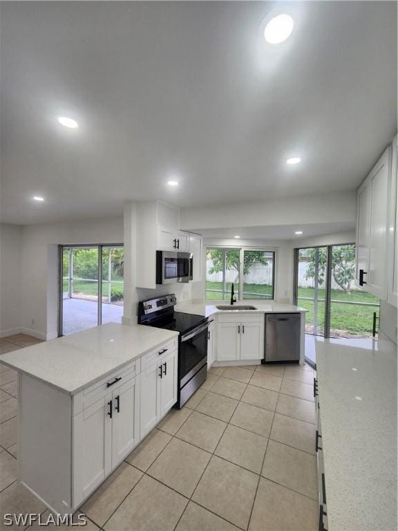 kitchen with white cabinetry, appliances with stainless steel finishes, light tile patterned flooring, and sink