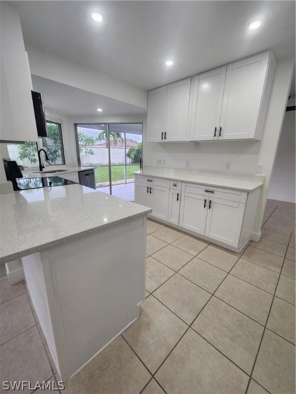 kitchen featuring sink, light stone counters, light tile patterned floors, stainless steel dishwasher, and white cabinets