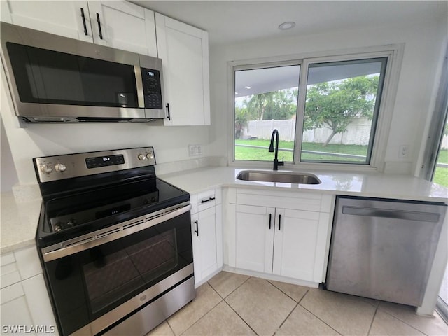 kitchen featuring appliances with stainless steel finishes, a wealth of natural light, sink, and white cabinets