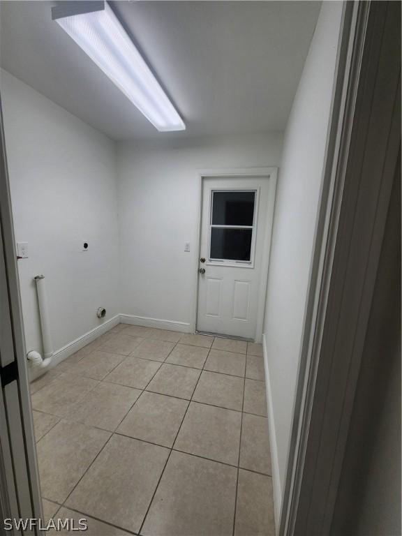 clothes washing area featuring electric dryer hookup and light tile patterned floors