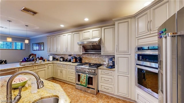 kitchen featuring sink, decorative backsplash, light stone countertops, cream cabinetry, and premium appliances