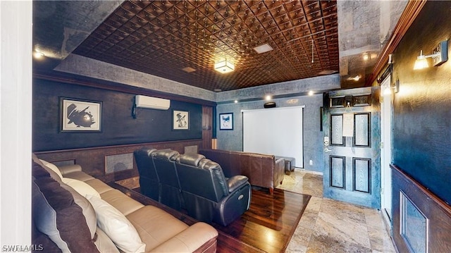 home theater featuring hardwood / wood-style flooring, a wall unit AC, and a tray ceiling