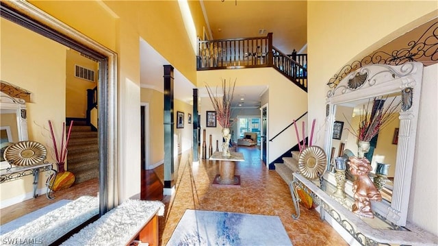 hall with tile patterned floors, crown molding, and a high ceiling