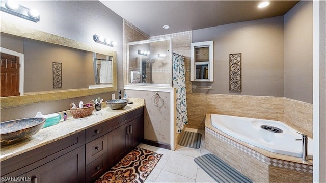 bathroom featuring tile patterned floors, tiled bath, and double sink vanity