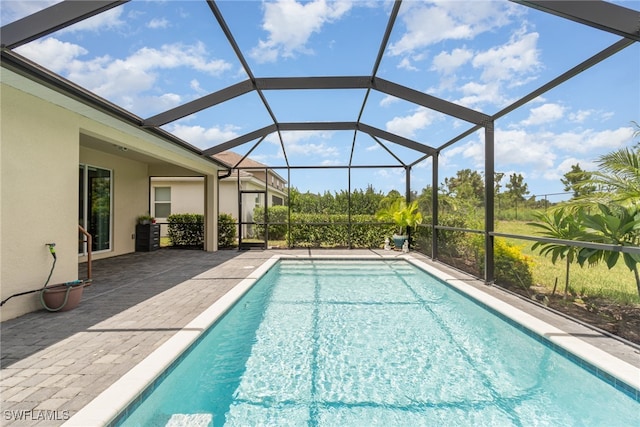 view of pool with glass enclosure and a patio