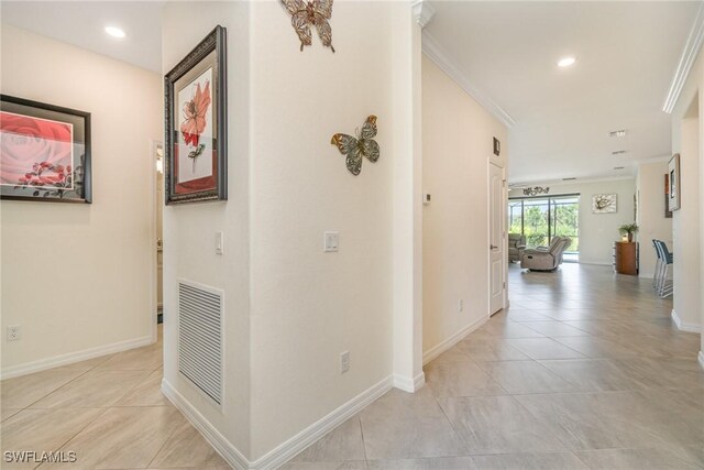 hallway with ornamental molding and light tile patterned floors