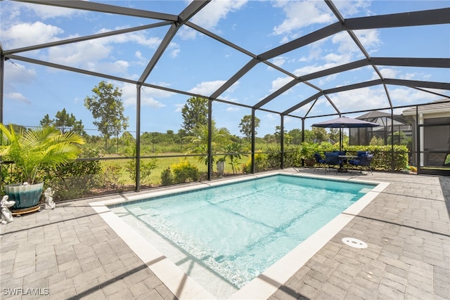 view of swimming pool featuring glass enclosure and a patio