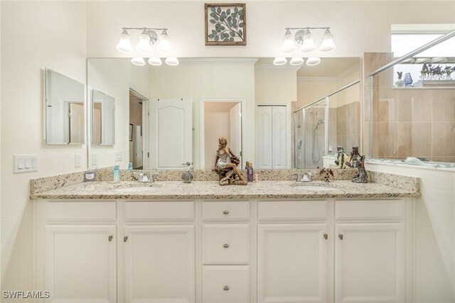 bathroom with a shower with shower door, dual bowl vanity, and crown molding