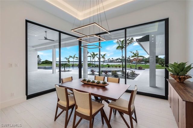 dining room with a tray ceiling, ceiling fan with notable chandelier, and a healthy amount of sunlight