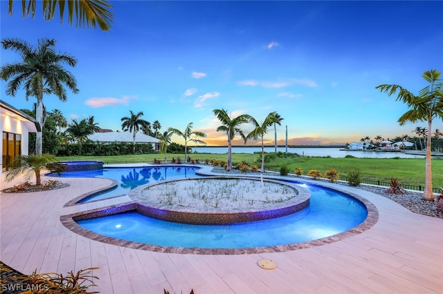 pool at dusk featuring an in ground hot tub and a water view