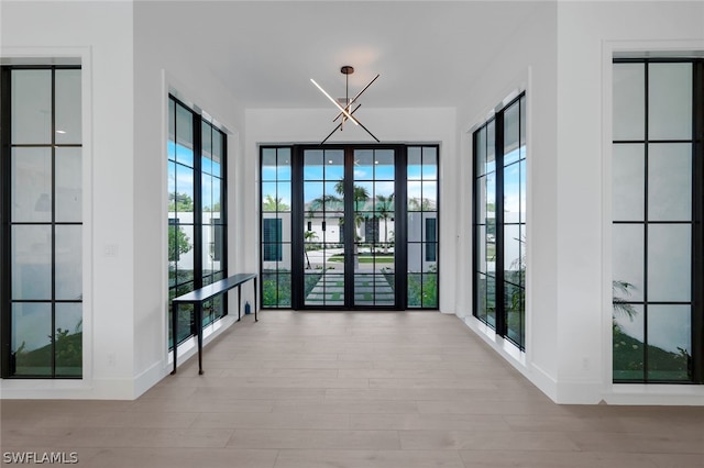 interior space featuring light hardwood / wood-style floors, french doors, and a chandelier