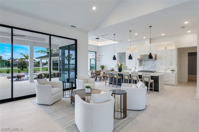 living room with light wood-type flooring, plenty of natural light, and a high ceiling