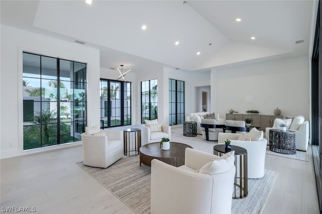 living room featuring high vaulted ceiling, light hardwood / wood-style floors, and a tray ceiling