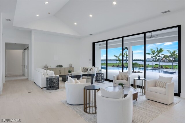 living room featuring lofted ceiling, a water view, light wood-type flooring, and ceiling fan