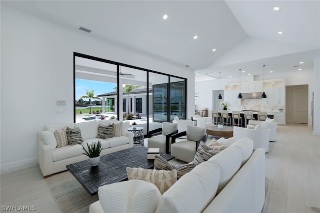 living room with light hardwood / wood-style floors and high vaulted ceiling