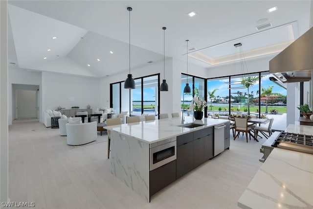 kitchen featuring appliances with stainless steel finishes, sink, light stone counters, and decorative light fixtures