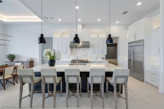 kitchen with pendant lighting, a spacious island, white cabinetry, and built in fridge