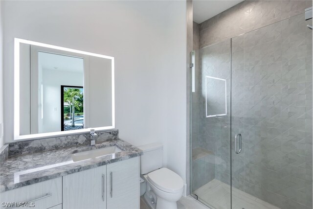 bathroom featuring toilet, vanity, and an enclosed shower