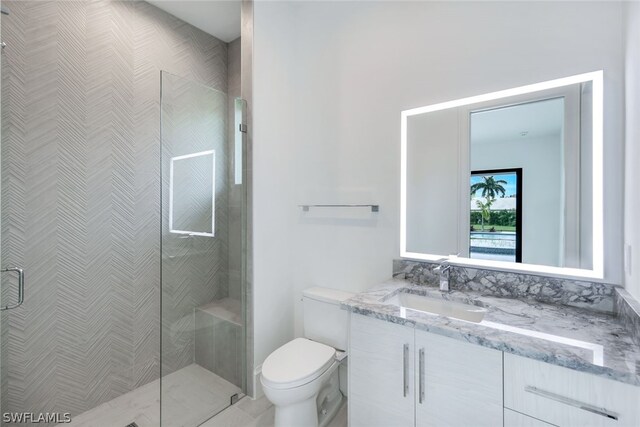 bathroom featuring a shower with shower door, vanity, and toilet