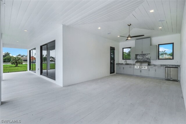 unfurnished living room with ceiling fan, sink, wooden ceiling, and light hardwood / wood-style flooring